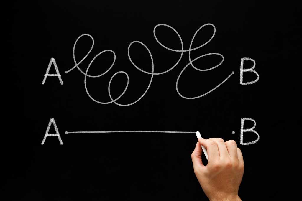 Hand drawing a white chalk line from point A to point B on a blackboard.